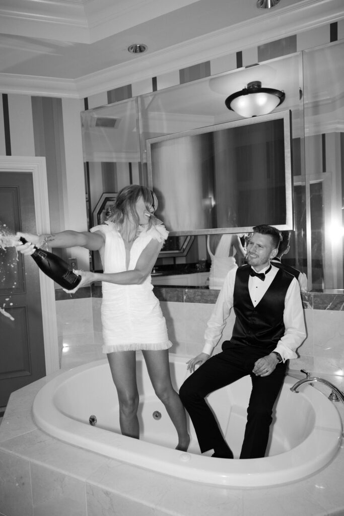 Bride and groom popping champagne in the bathtub