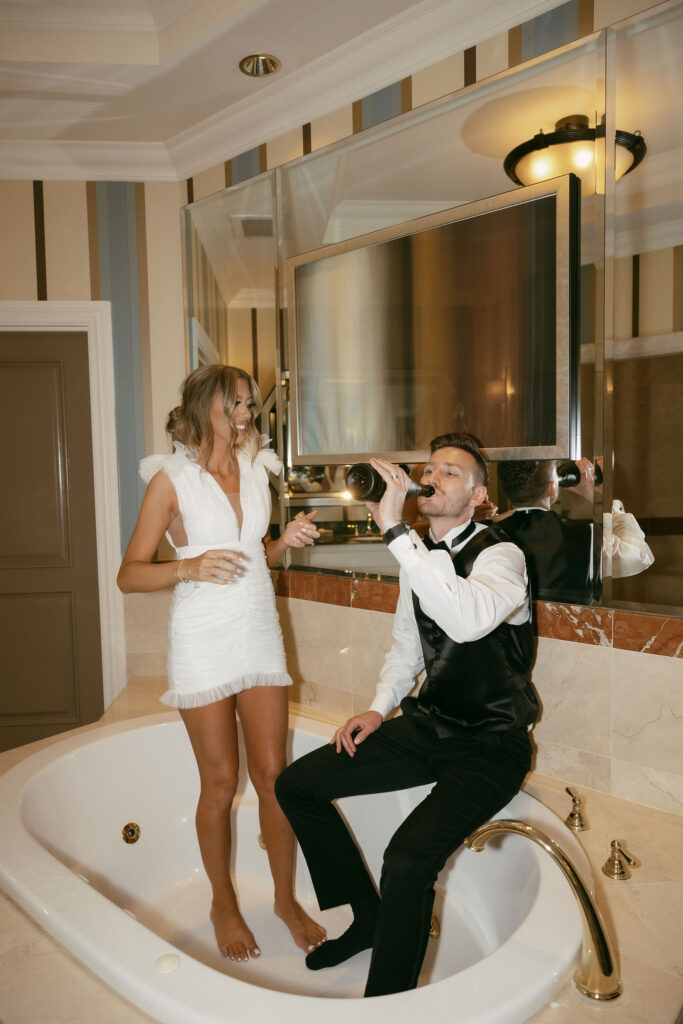 Bride and groom popping champagne in the bathtub