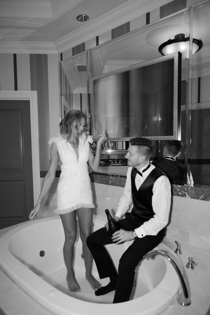 Bride and groom popping champagne in the bathtub