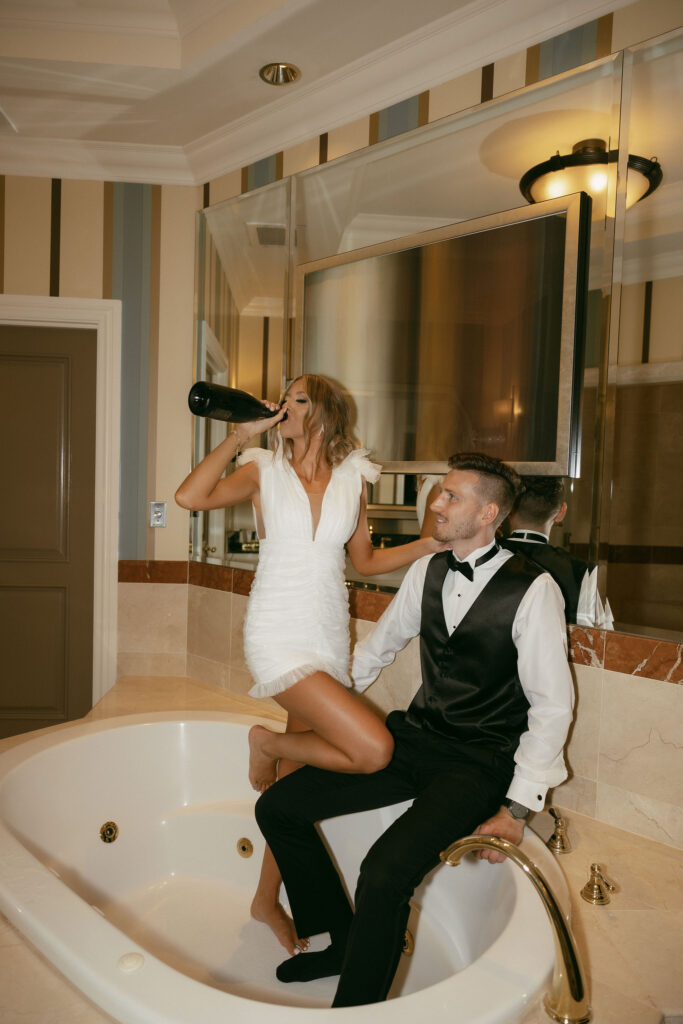 Bride and groom popping champagne in the bathtub