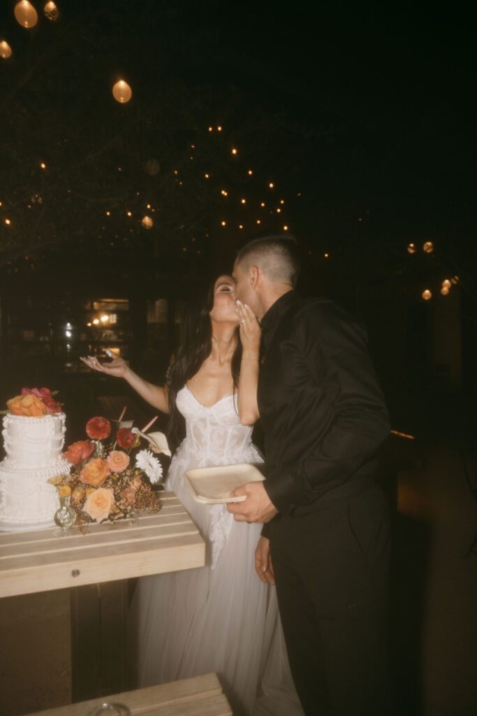 Bride and groom kissing after cutting into their wedding cake