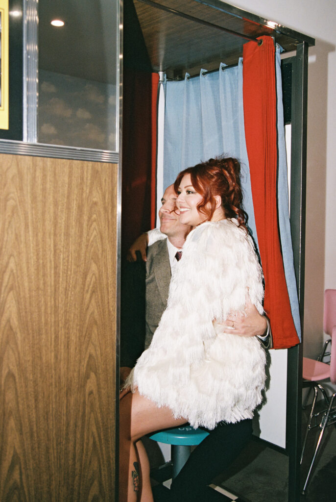 Bride and groom taking photos in Sure Thing Chapels vintage analog photobooth 