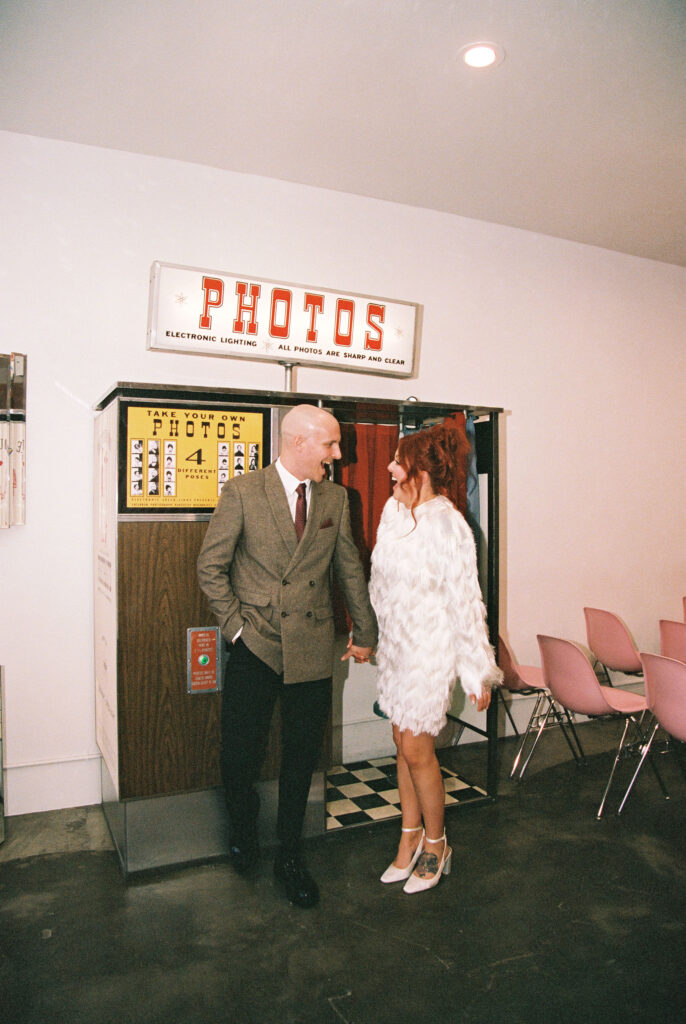 Bride and groom taking photos in Sure Thing Chapels vintage analog photobooth 