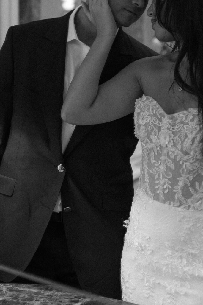 Close up black and white shot of a bride holding her grooms face lovingly. 