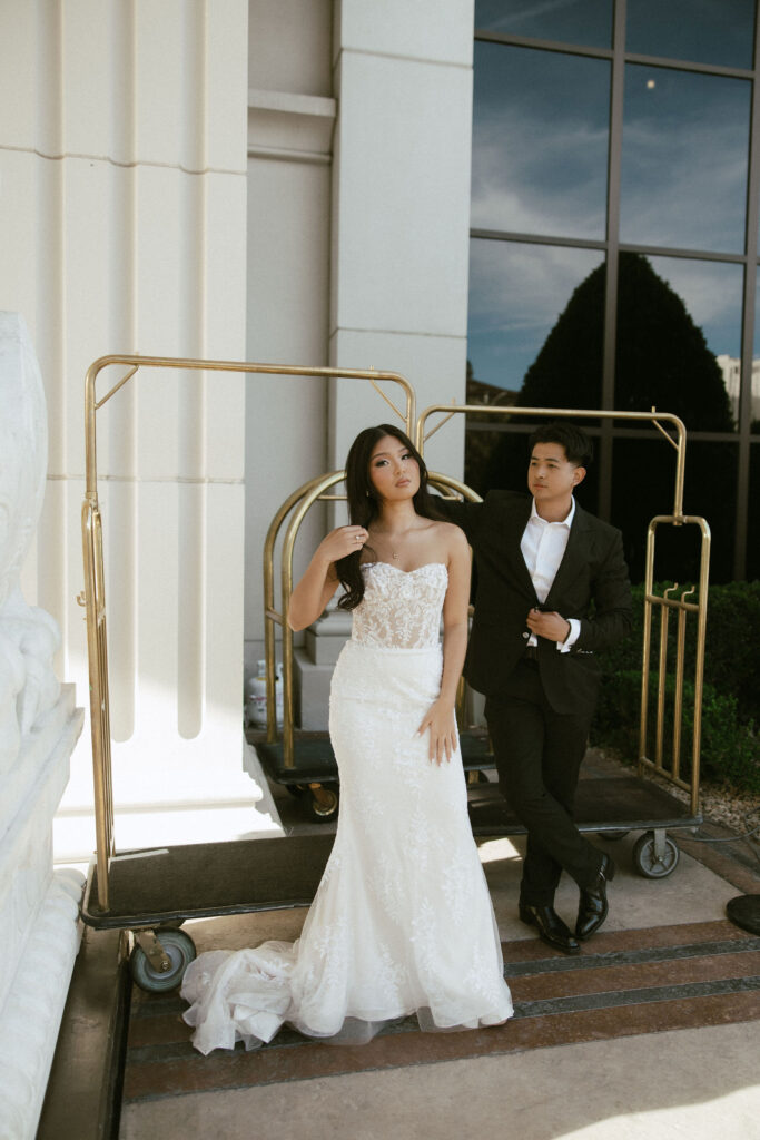 Bride and groom posing with hotel luggage carts at Caesars Palace in Las Vegas