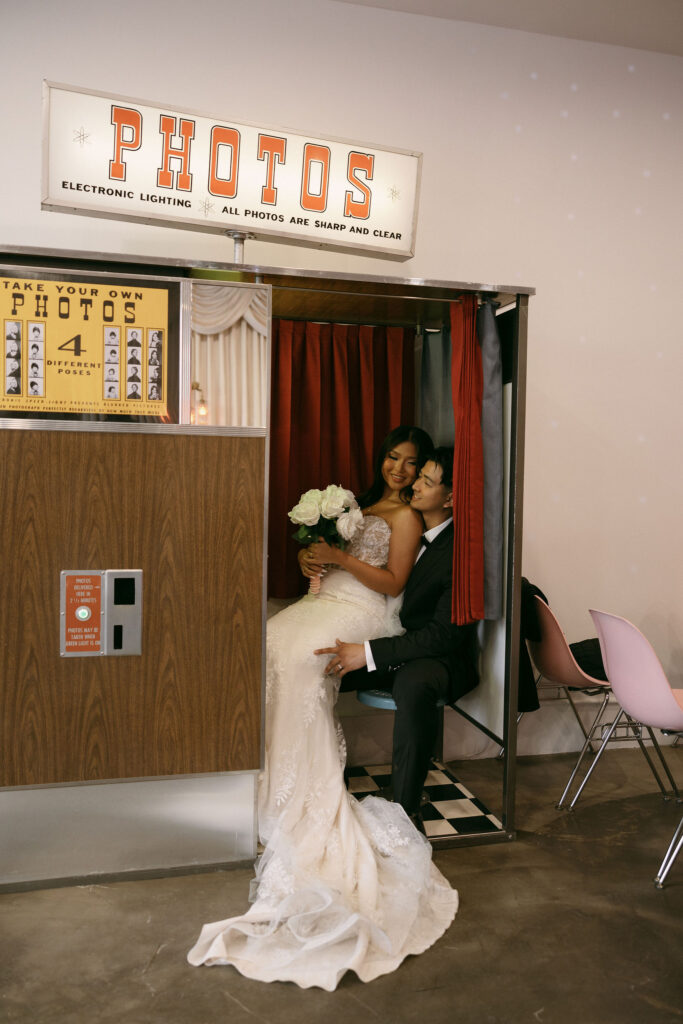 Bride and groom taking photos in Sure Thing Chapels vintage analog photobooth.