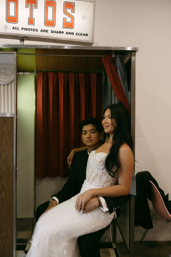 Bride and groom taking photos in Sure Thing Chapels vintage analog photobooth.