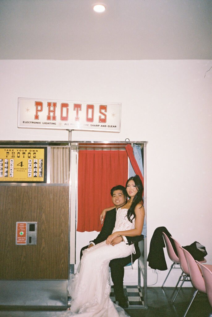 Film photo of a bride and groom sitting in Sure Thing Chapels analog photobooth. 