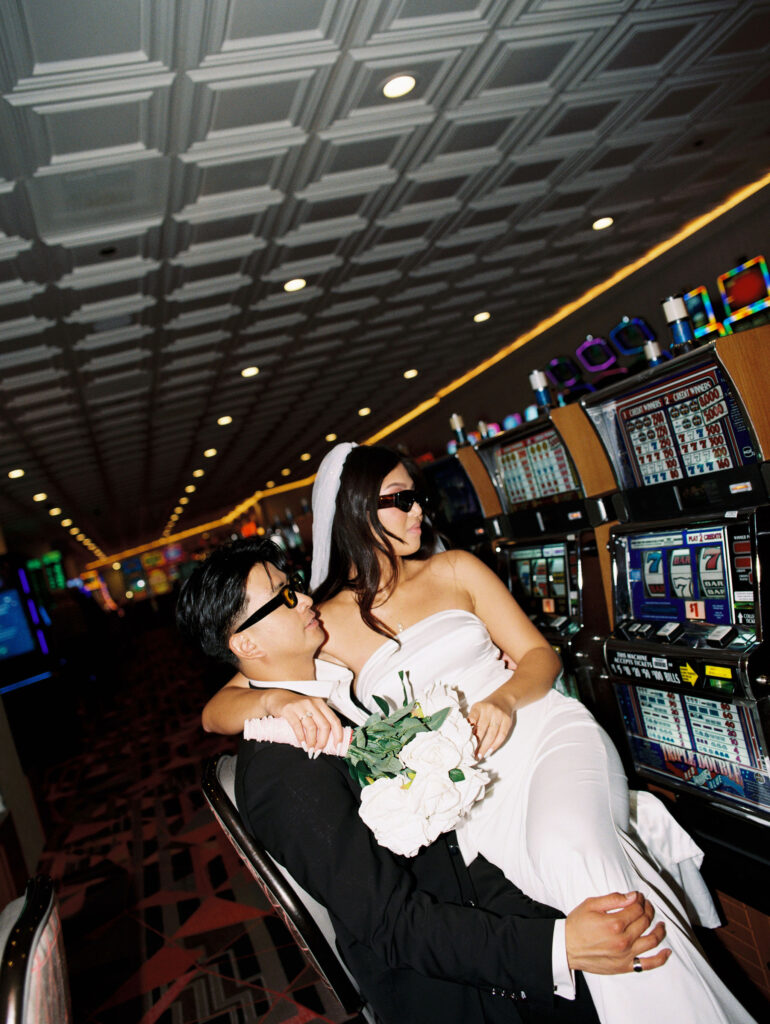 Film photos of a bride and groom playing slots in Las Vegas.