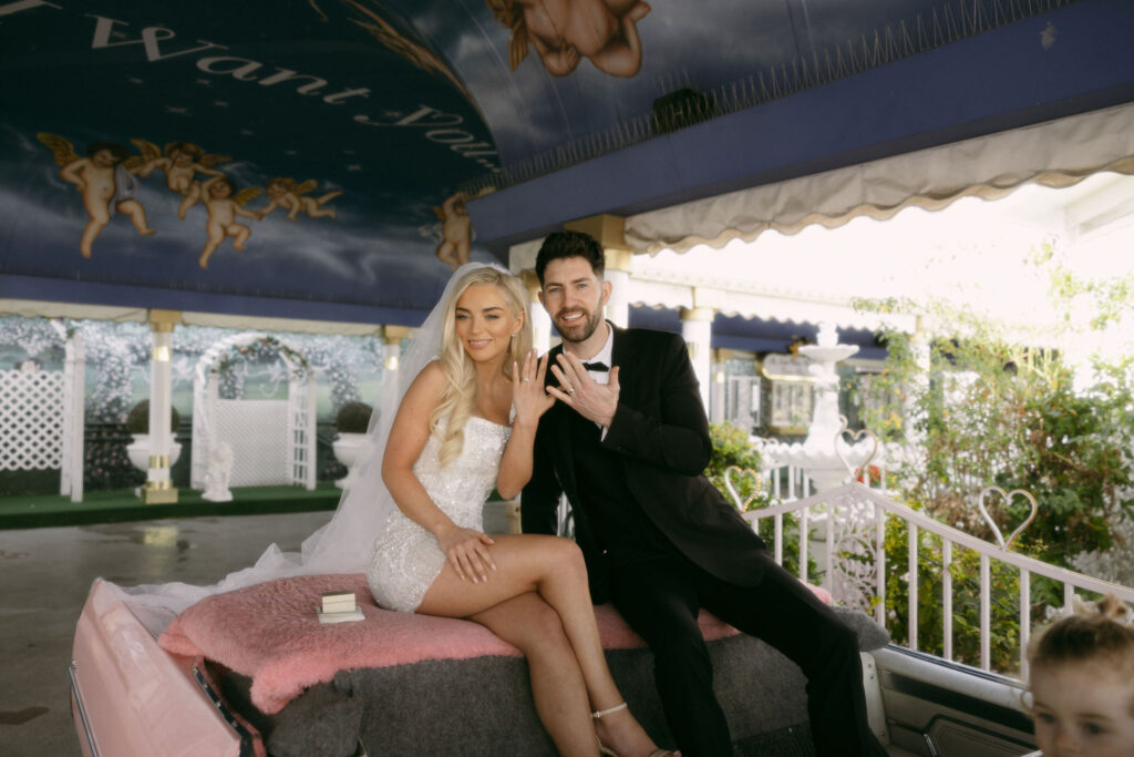 Bride and groom posing for photos after their Little White Chapel Pink Cadillac ceremony