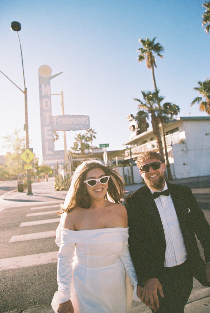 Bride and groom walking in downtown Las Vegas in front of Fergusons motel