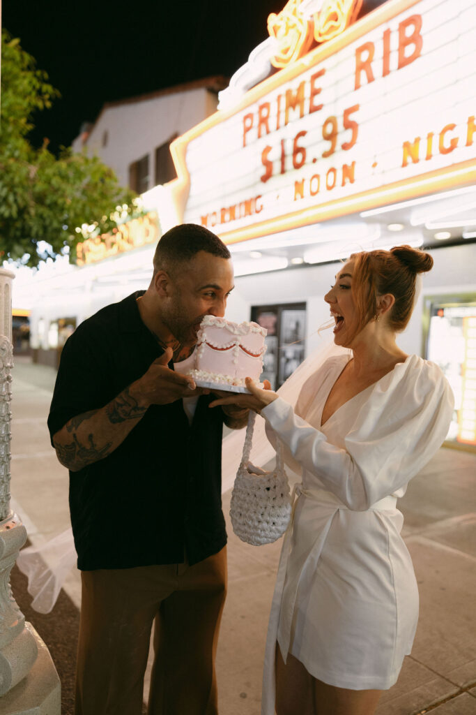 Groom taking a bite into their pink elopement cake