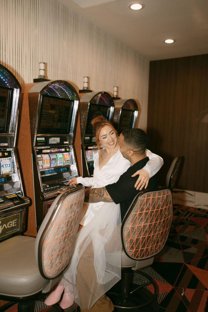 Bride and groom sitting at the slots in Las Vegas for their wedding photos