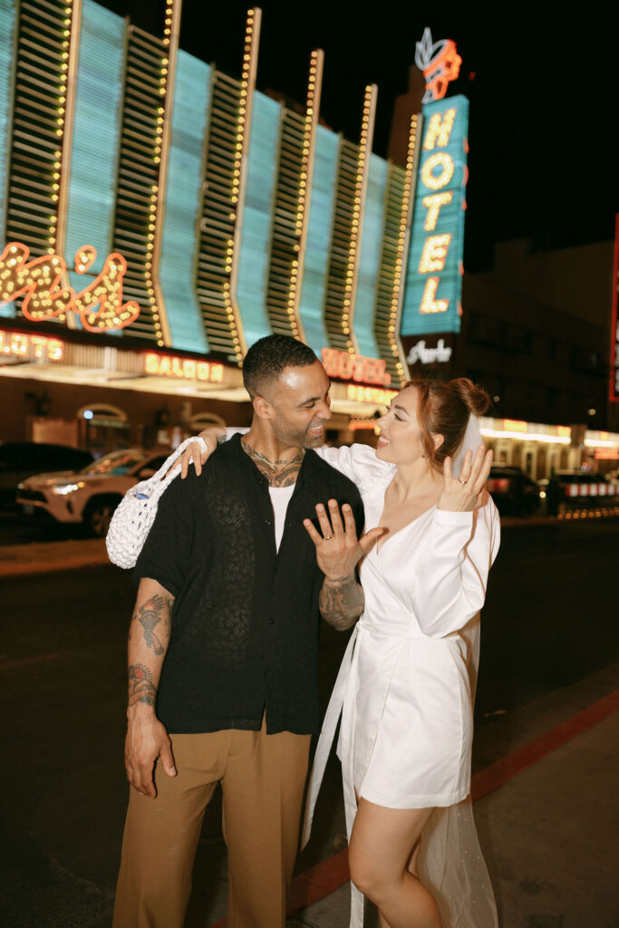 Flash photo of a bride and groom showing off their wedding rings in downtown Las Vegas