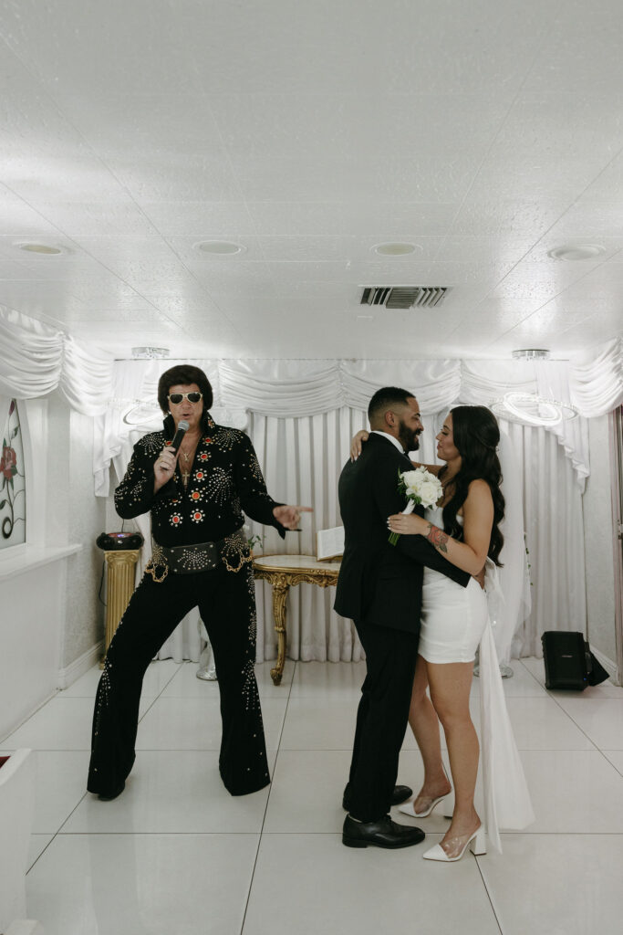 Bride and groom getting serenaded to by an Elvis impersonator at The Little White Wedding Chapel