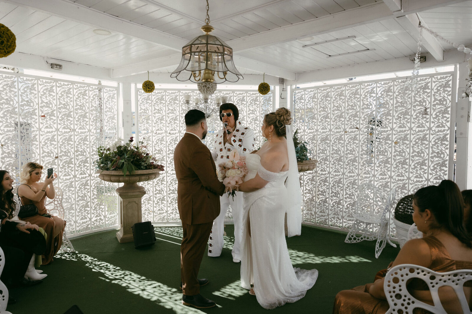 Bride and groom getting married by an Elvis impersonator in the Gazebo at The Little White Wedding Chapel