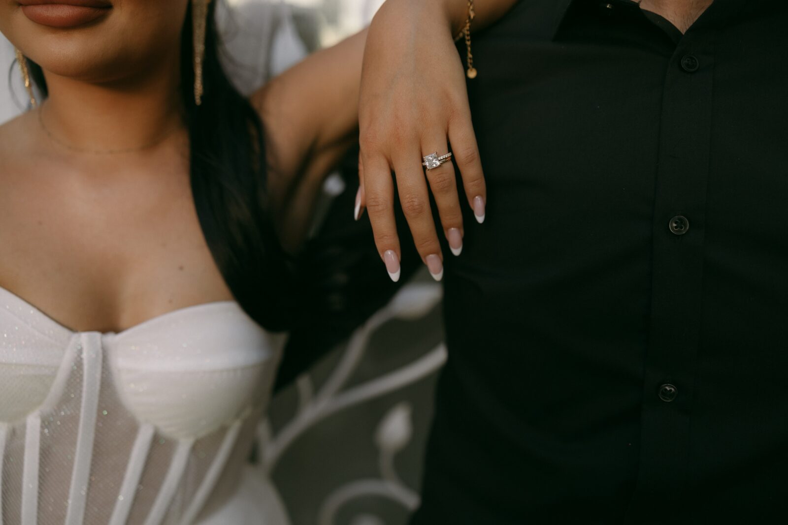 Close up shot of a bride resting her hand on the grooms shoulder and showing off her wedding ring