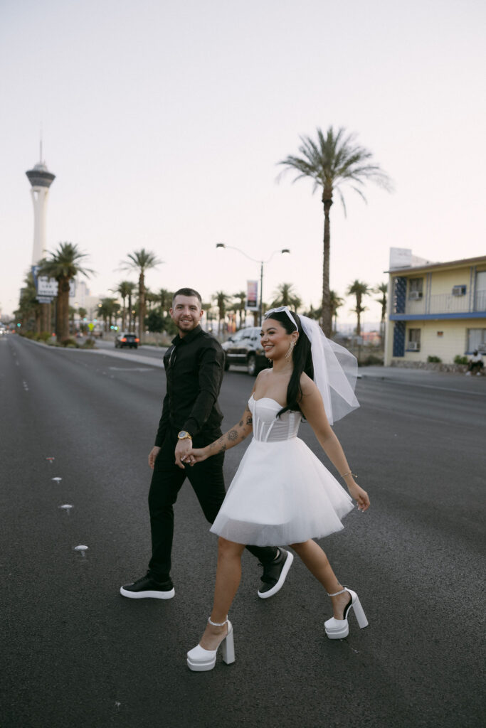 Bride and groom holding hands as they cross the street in Las Vegas