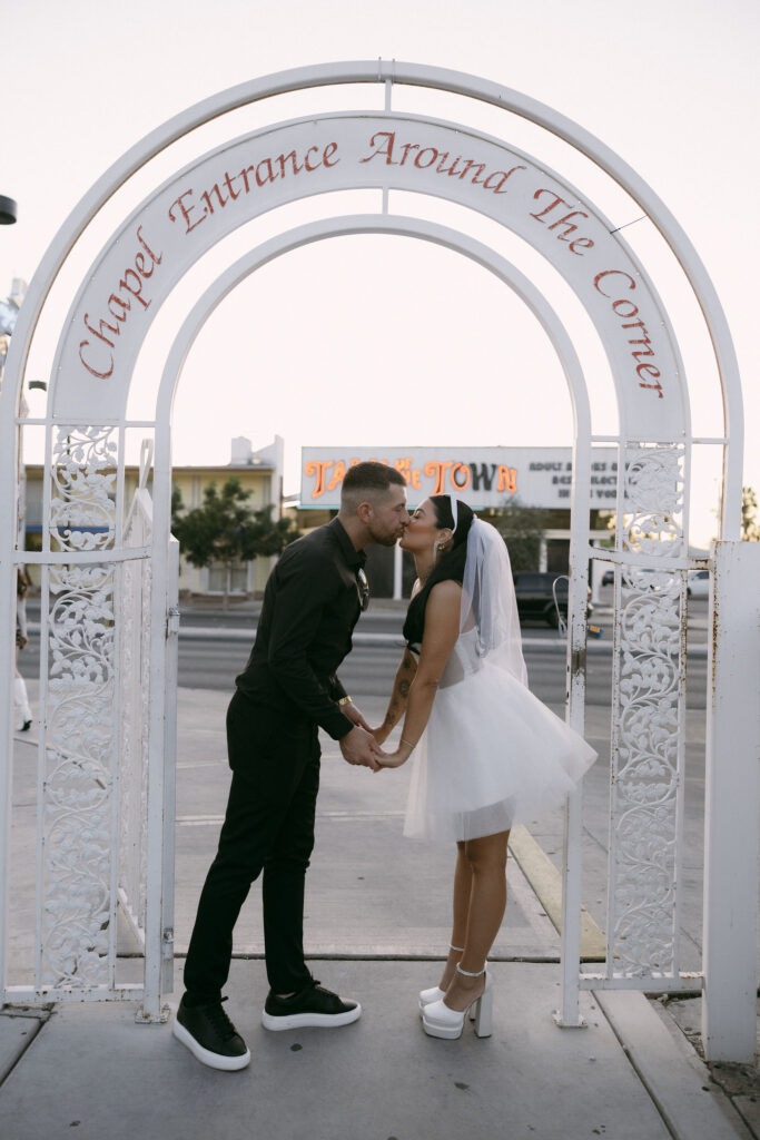 Bride and groom kissing in front of The Little White Wedding Chapels entrance