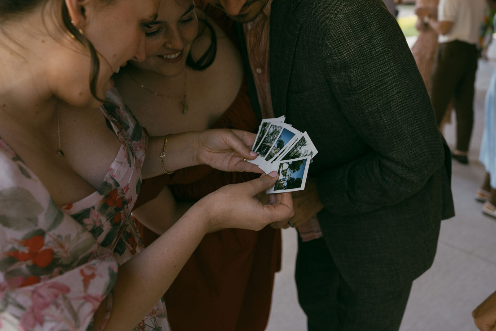 Wedding guests looking through wedding day polaroid's from a summer camp wedding in Wisconsin