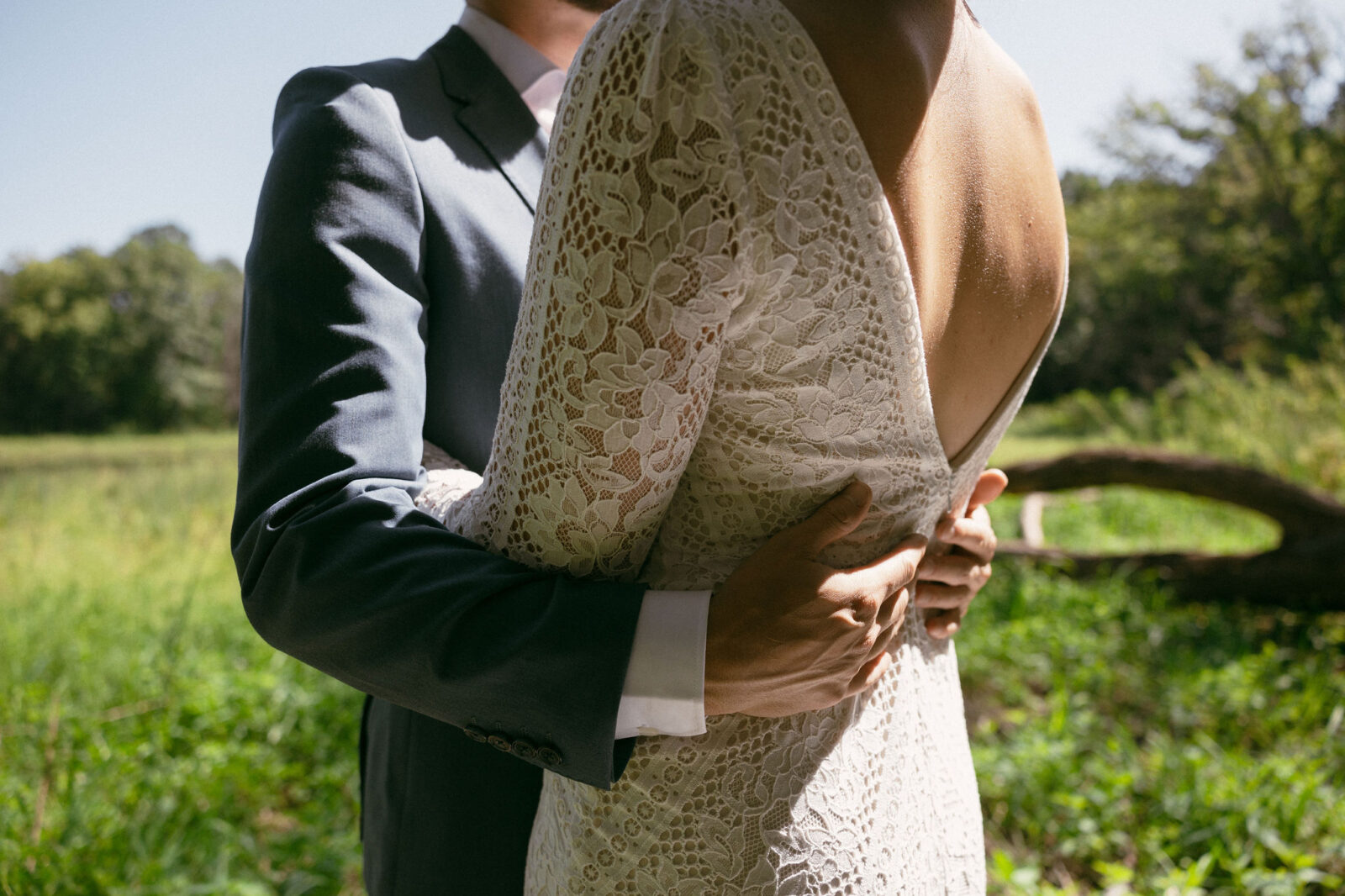 Close up shot of a groom holding his bride around her waist