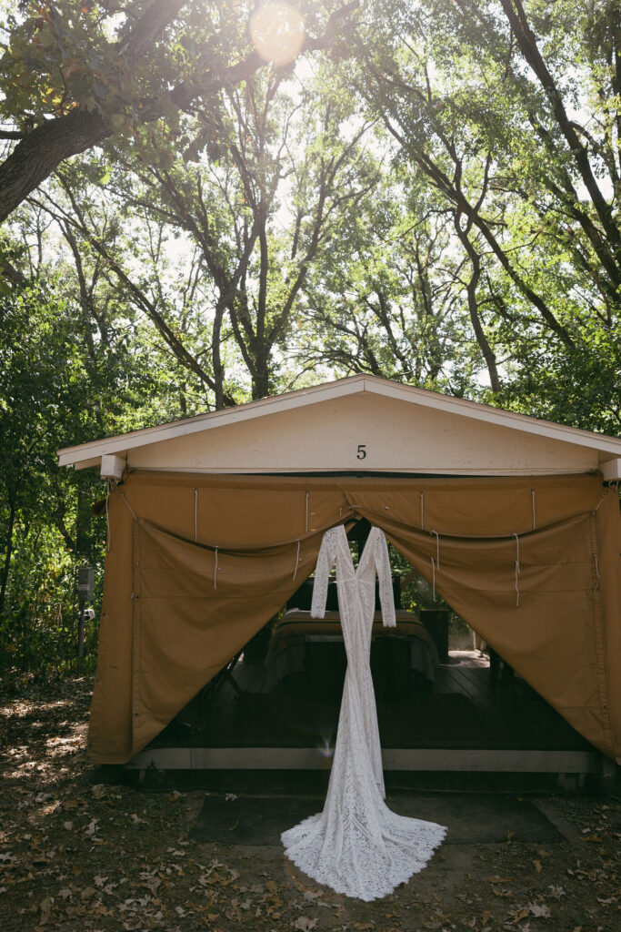 Wedding dress hanging from a tent during a summer camp wedding in Wisconsin at Camp Kettlewood