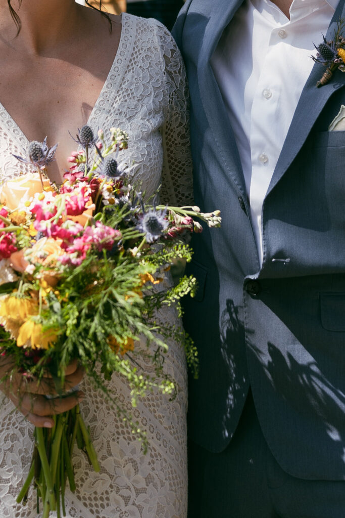 Close up shot of a bride and groom wedding a wildflower summer camp wedding bouquet