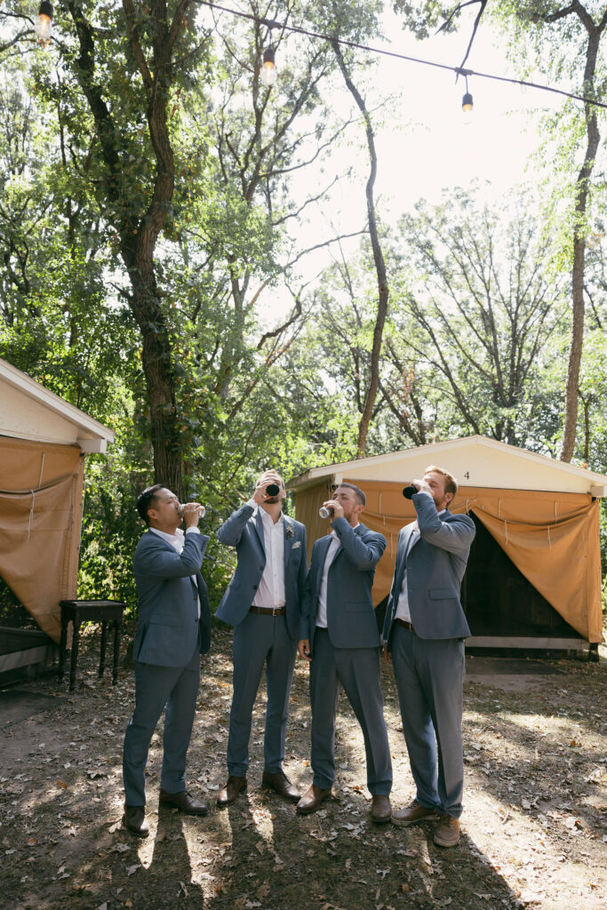 Groom and his groomsmen drinking beers from a summer camp wedding in Wisconsin at Camp Kettlewood