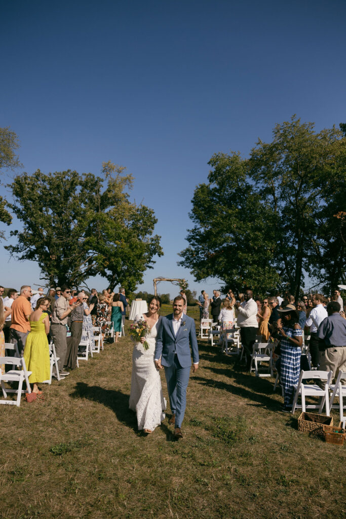 Bride and groom walking back down the aisle as husband and wife during their summer camo wedding ceremony in Wisconsin