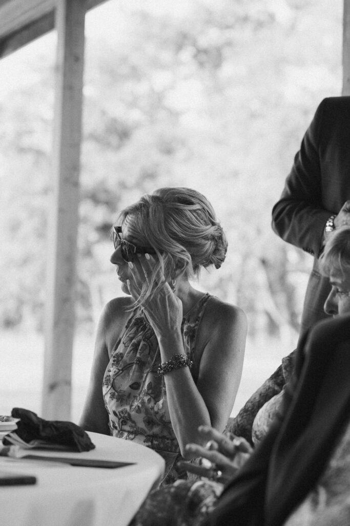 Black and white candid wedding photo of a guest getting emotional during speeches