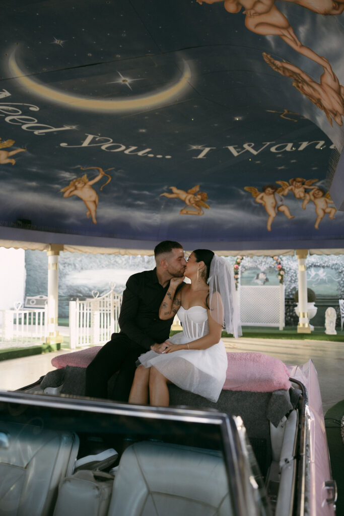 Bride and groom kissing in the Pink Cadillac during their Little White Wedding Chapel elopement in Las Vegas