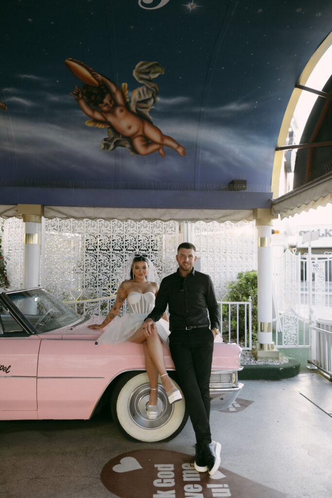 Bride and groom posing with the Pink Cadillac at Little White Wedding Chapel in Las Vegas