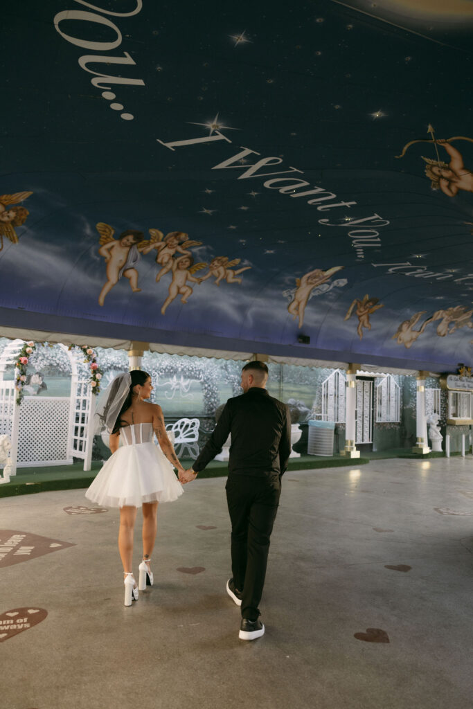 Bride and groom holding hands as they walk in The Tunnel of Love at The Little White Wedding Chapel