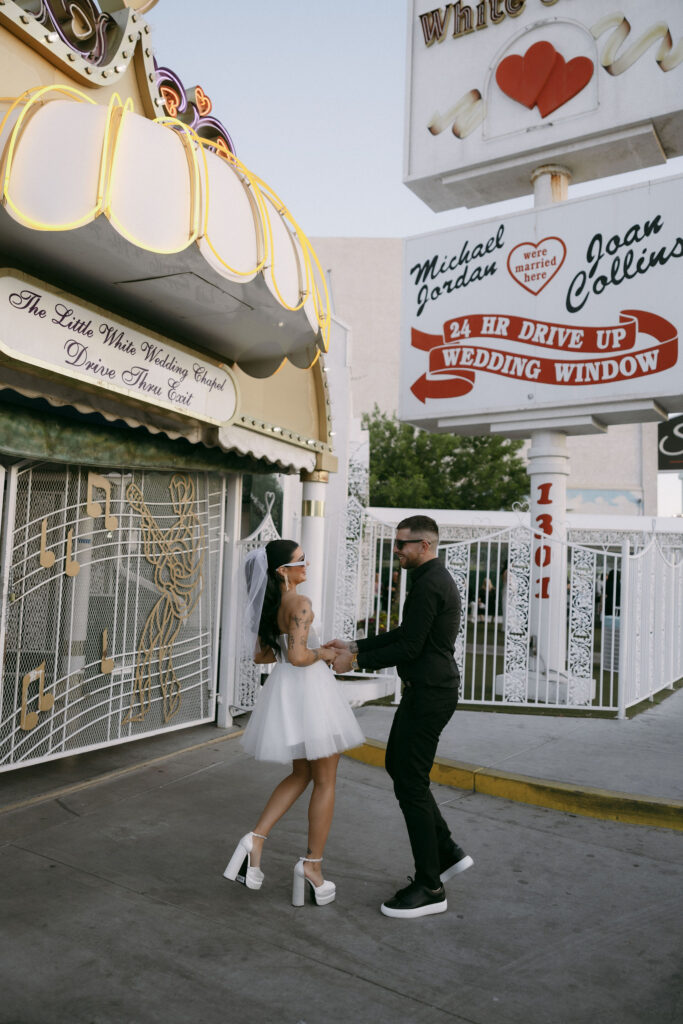 Bride and groom dancing in front of the Little White Wedding Chapel sign