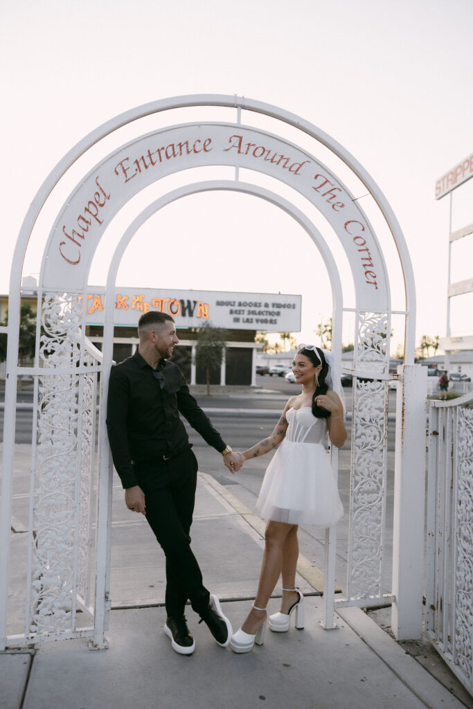 Bride and groom posing for portraits at the chapel entrance around the corner at Little White Wedding Chapel