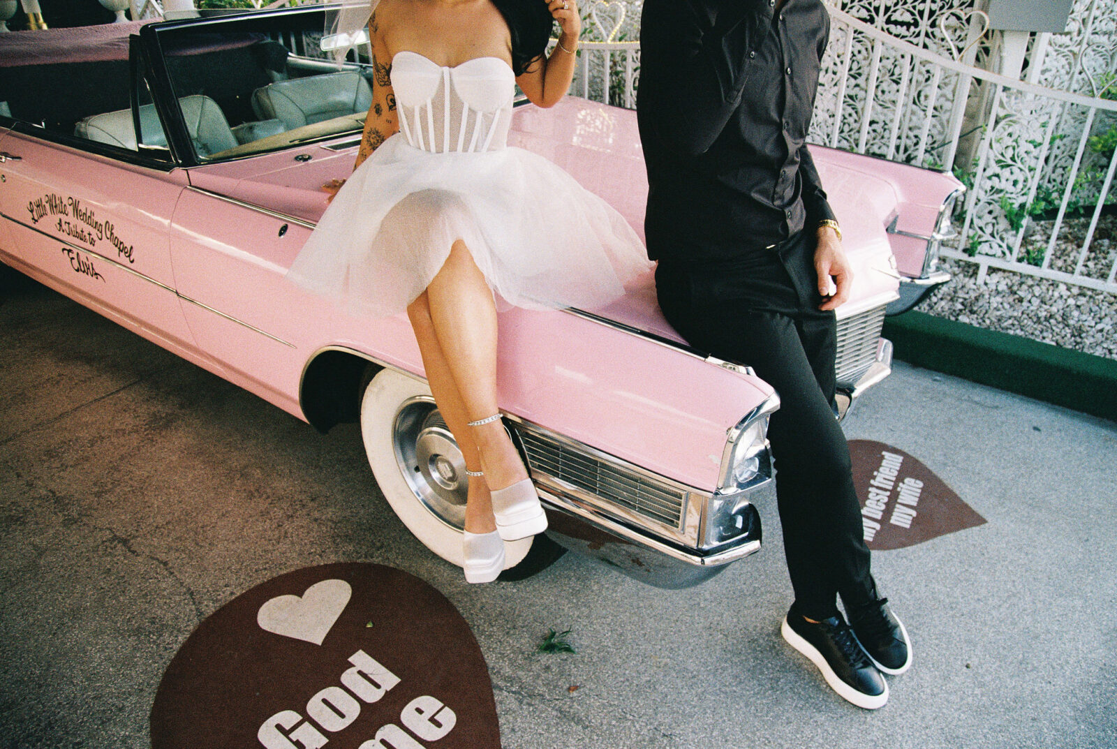 Bride and groom sitting on the Pink Cadillac on film