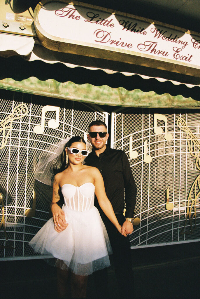 Bride and groom wearing sunglasses for their film elopement photos at The Little White Wedding Chapel in Las Vegas