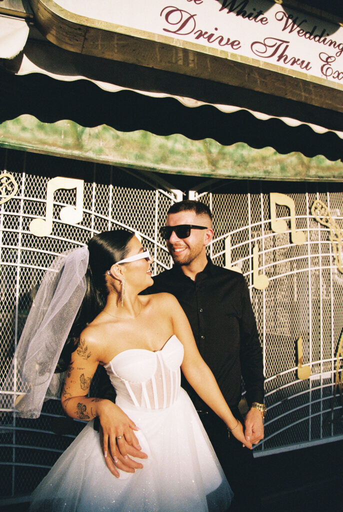 Bride and groom wearing sunglasses for their film elopement photos at The Little White Wedding Chapel in Las Vegas