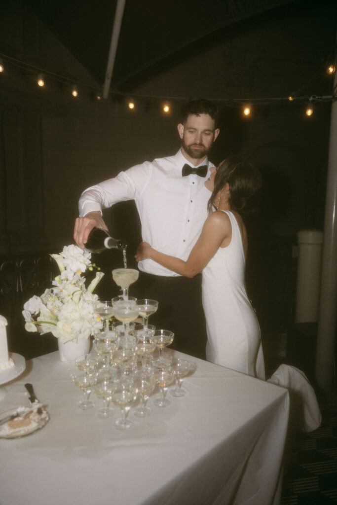 Bride and groom posing during their champagne tower pour