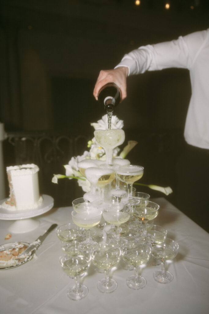 Groom pouring champagne into their champagne tower