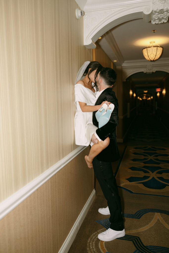 Groom kissing his bride against a hallway wall