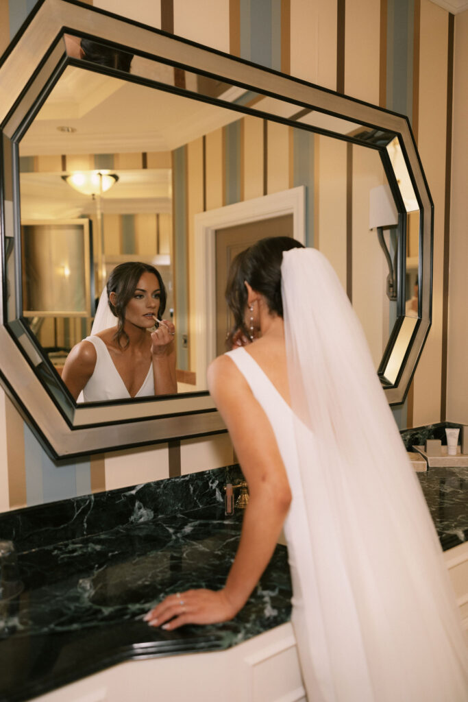 Bride touching up her lipstick in the mirror