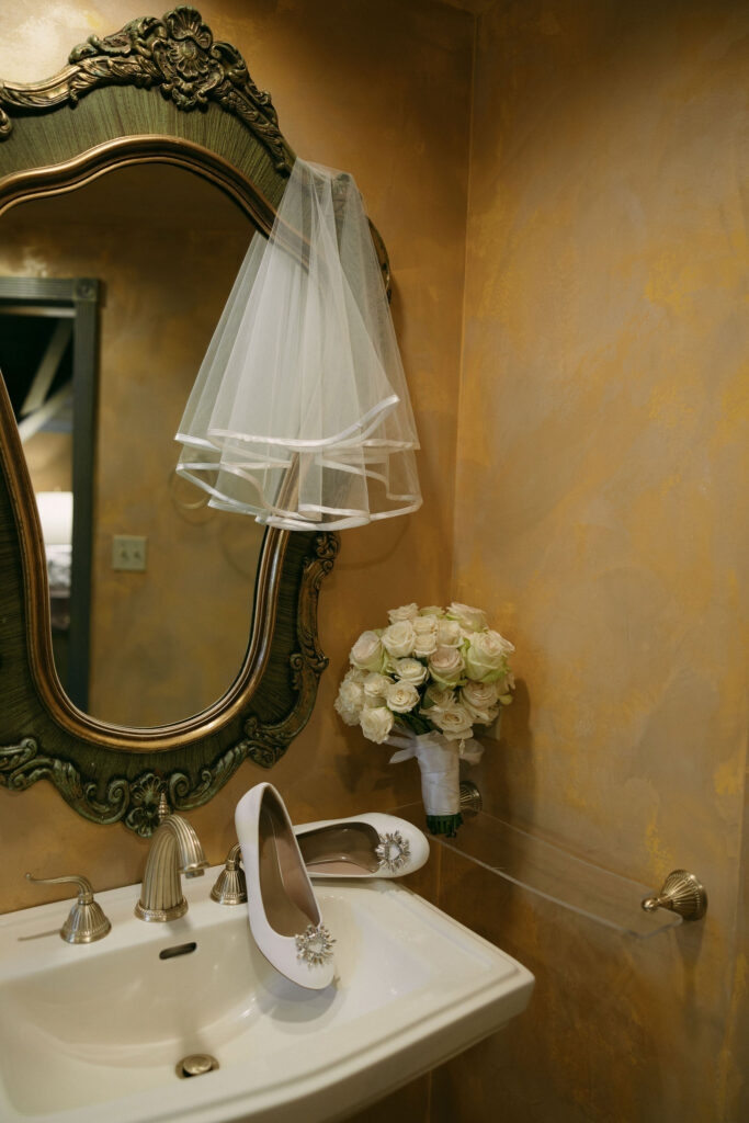 Brides bouquet, heels and veil hanging in the bathroom for her wedding detail shots