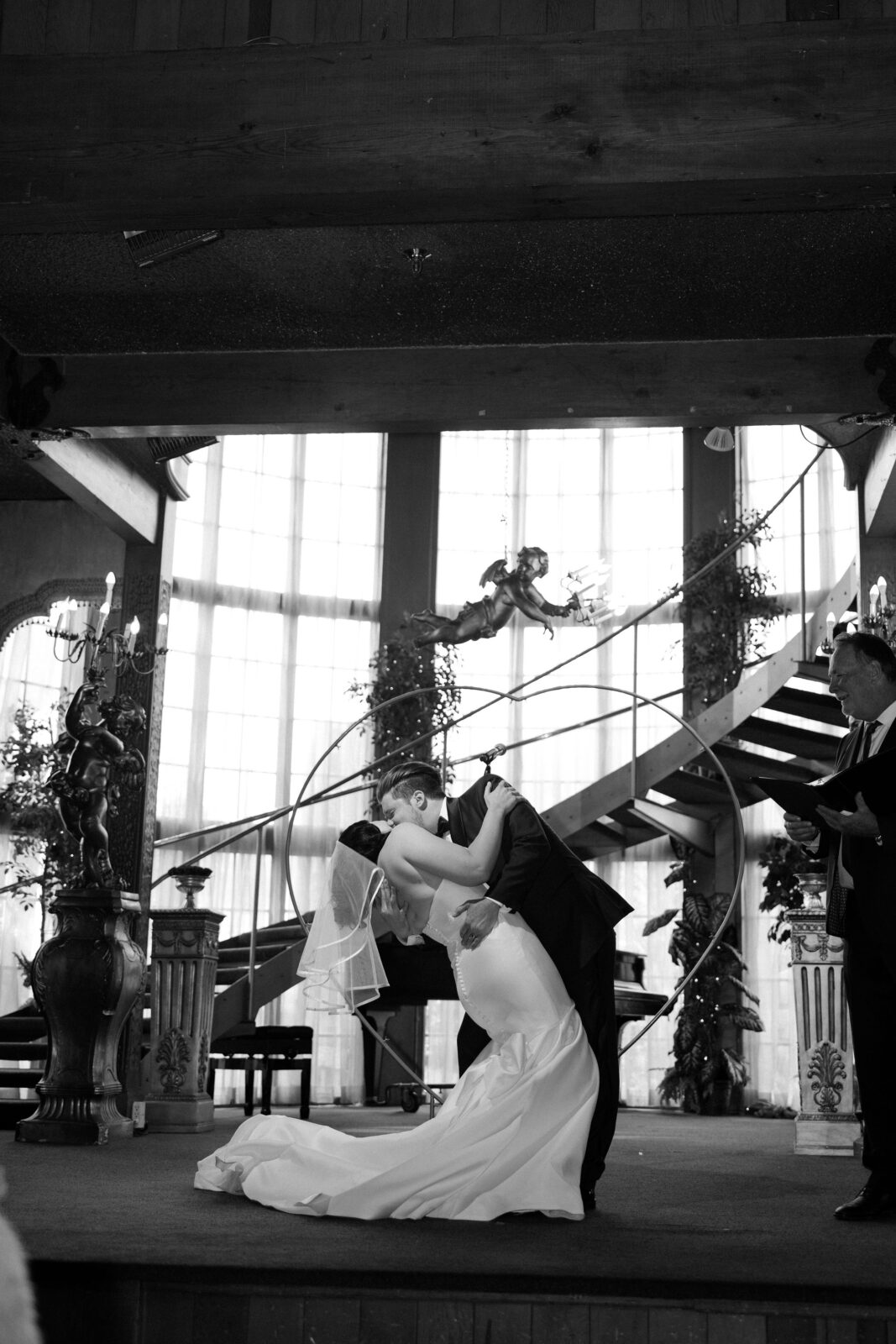 Black and white photo of a bride and groom kissing during their Madonna Inn wedding ceremony on The Main Dance Floor