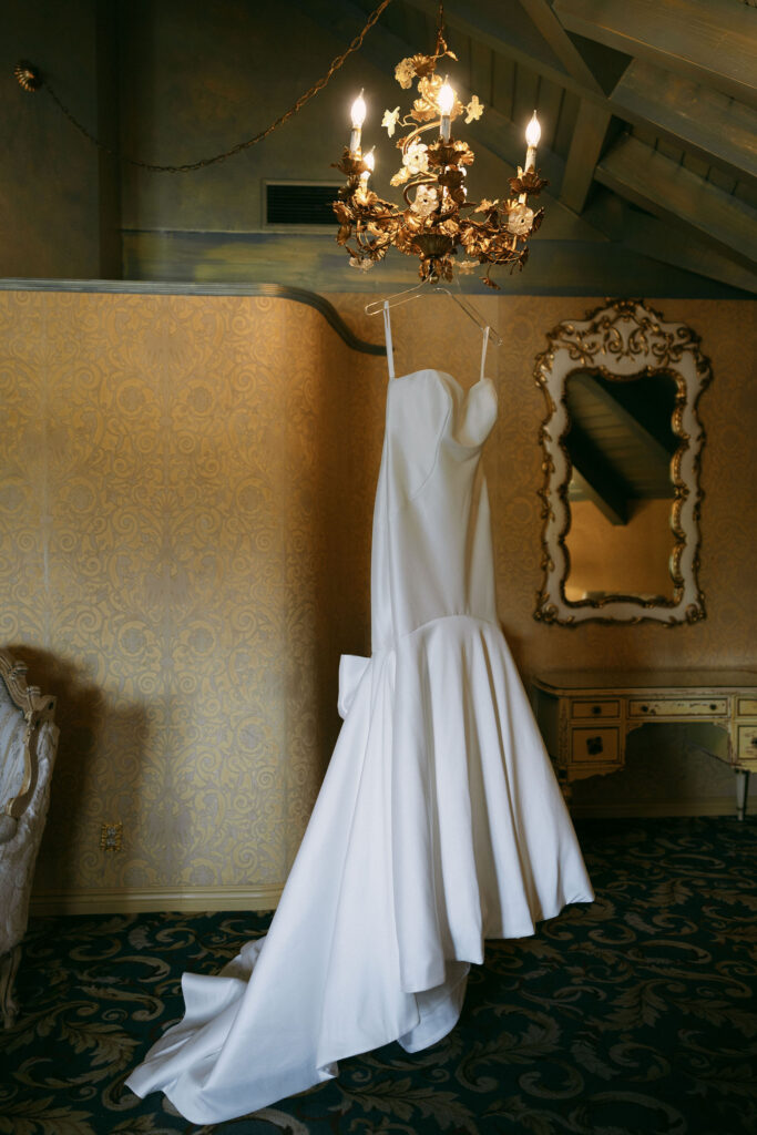 Brides wedding dress hanging from a chandelier 