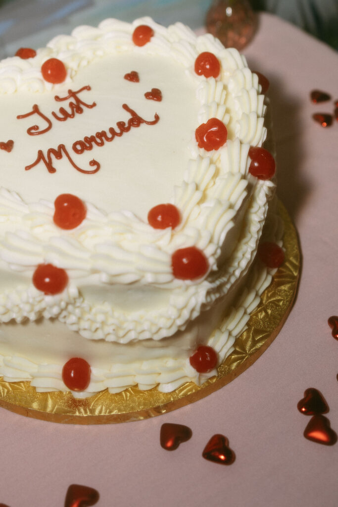 A white vintage-inspired cake that says just married with cherries
