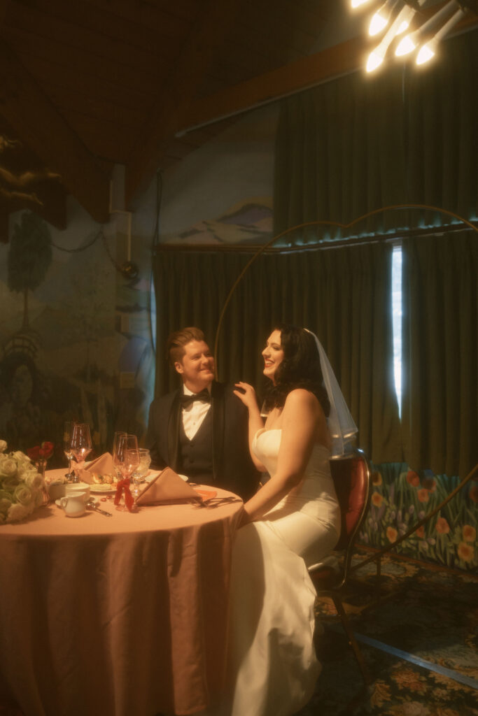 Bride and groom at the sweethearts table during their indoor Madonna Inn wedding reception