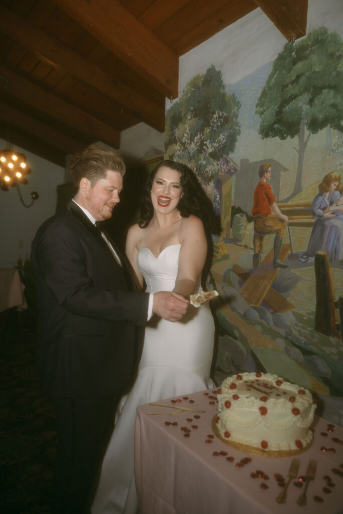 Bride and groom cutting into their white wedding cake