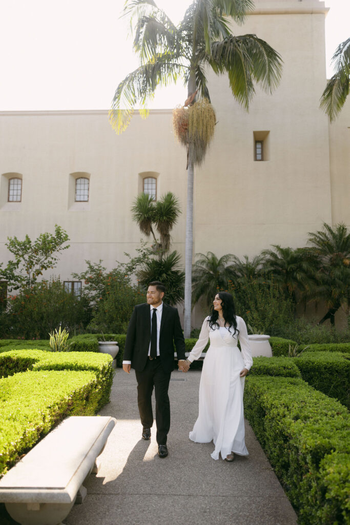 Couple strolling through Alcázar Garden for their Balboa Park engagement photos in California