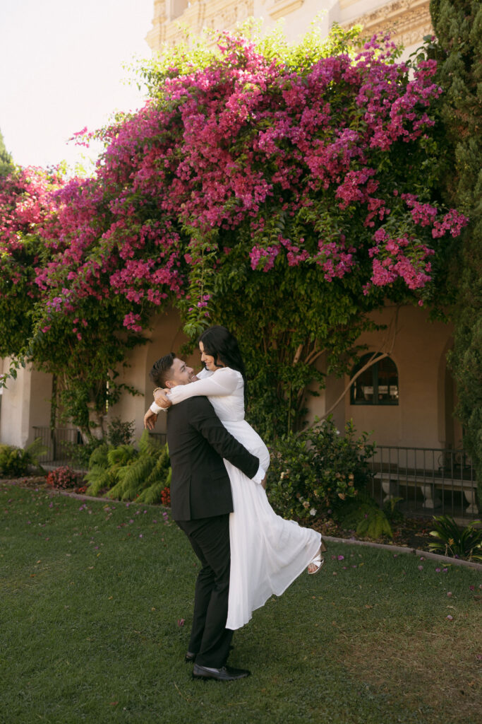 Man picking up his fiancé during their Balboa Park engagement photoshoot